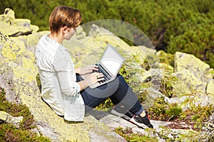 Woman sitting on the hill with laptop