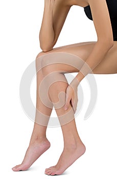 Woman sitting and holding her beautiful Healthy long leg with massaging calf in pain area.