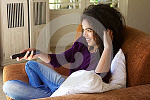 Woman sitting at home with remote control watching tv