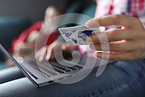 Woman sitting home sofa with laptop and credit card photo