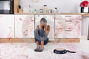 Woman Sitting On Kitchen Floor With Spilled Food