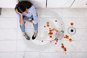 Woman Sitting On Kitchen Floor With Spilled Food