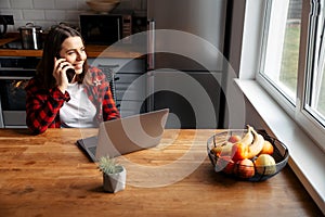 Woman sitting on the kitchen using laptop