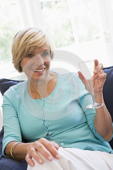Woman sitting in living room with drink smiling