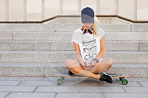 Woman sitting on longboard and texting