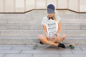 Woman sitting on longboard and texting photo