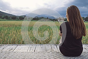 A woman sitting and looking at a beautiful rice field onward with feeling relaxed