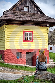 Woman sitting and looking on colorful wooden cottage in historical village Vlkolinec at Slovakia