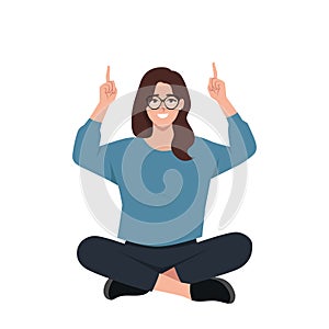 Woman sitting lotus pose on the floor and pointing index fingers up