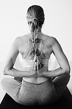 A woman sitting in the lotus position with her hands in anjali mudra on her back
