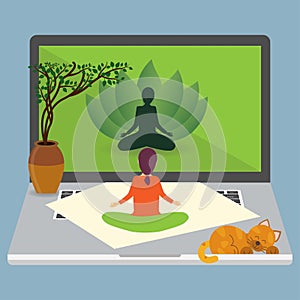 Woman sitting in lotus position on a mat on a big laptop and looking at the screen, online yoga concept