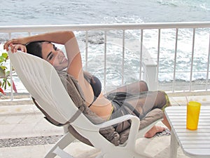 Woman sitting in a lounge chair by the beach