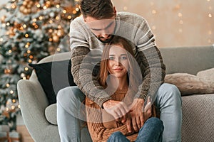 Woman is sitting. Lovely young couple are celebrating New Year at home