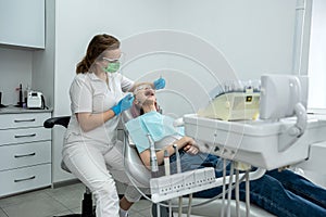 woman is sitting in medical chair while female dentist is fixing her teeth in a dental clinic.