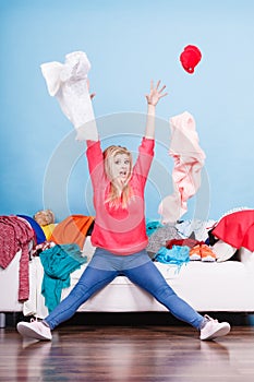 Woman sitting on messy couch throwing clothes