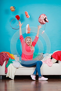 Woman sitting on messy couch throwing clothes