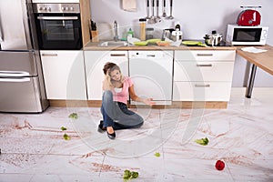 Woman Sitting On Messy Kitchen Floor