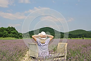 Woman sitting in middle of lavender field and amazing nature enjoying view