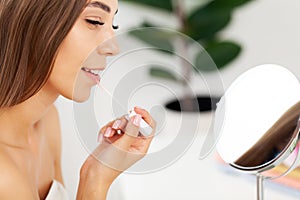 Woman sitting by the mirror and applying makeup