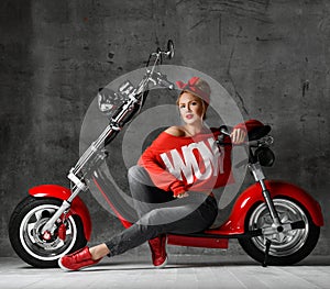 Woman sitting on motorcycle bicycle scooter retro pinup style in red blouse and jeans