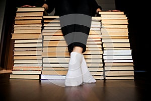 Woman sitting on mountain of books archives.