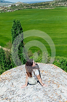 woman sitting on a mountain nature green field look to the side