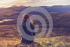 Woman sitting on mountain top and contemplating