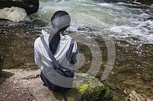 Woman sitting near a flowing water stream