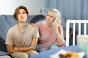 Woman sitting near her sad son and calling to doctor