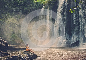 Woman sitting near waterfall enjoying the sun, Phnom Koulen at Siem Reap, Cambodia