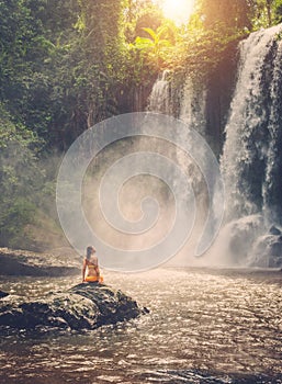 Woman sitting near waterfall enjoying the sun, Phnom Koulen at Siem Reap, Cambodia