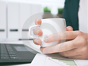 Woman sitting in office and holding coffee cup. Enjoyment and work life balance. freelance and distance job concept with copy