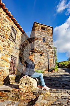 Woman sitting on an old millstone in the picturesque village of Patones de Arriba, Madrid. photo