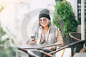 Woman sitting on open terrace in street cafe. Autumn time in cit