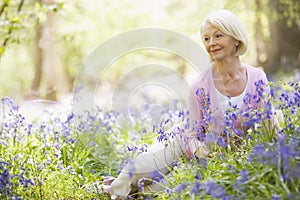 Woman sitting outdoors with flowers smiling