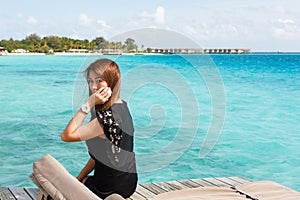 Woman sitting at overwater villa room at Maldives.