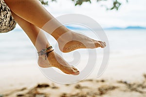 Woman sitting on palm tree at tropical beach