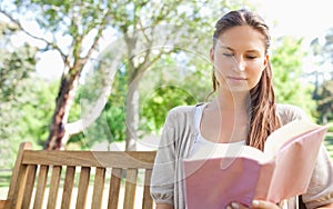 Woman sitting on a park bench while reading a book