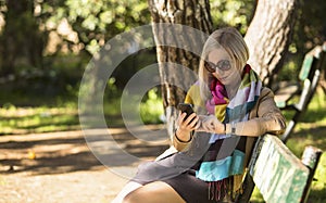 woman sitting on a Park bench and typing on his smartphone.