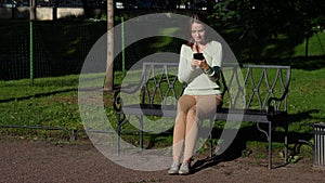 Woman sitting in park using smartphone