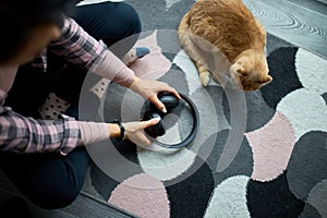 Woman Sitting on Patterned Rug Adjusting Headphones Next to Orange Cat