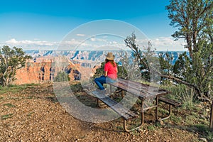 Woman Sitting on Picnic Table Looking at The Grand Canyon