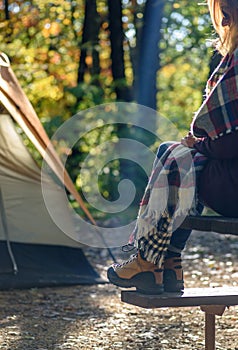 woman sitting on picnic table outside tent on campsite on a crisp early fall morning