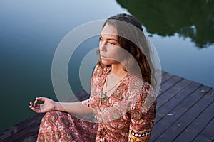 Woman sitting at the pier in lotus position