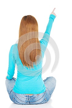 Woman sitting and pointing up, back view.