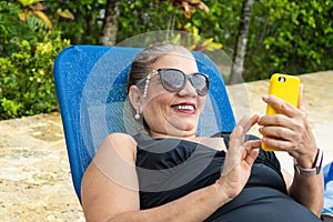 Woman sitting poolside and checking smartphone