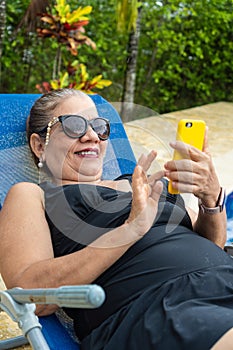 Woman sitting poolside and checking smartphone