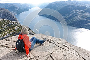 Woman sitting on Pulpit Rock / Preikestolen, Norway