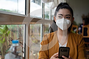 woman sitting and putting on a medical mask to protect from virus infection airborne respiratory diseases at the cafe