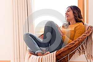 Woman sitting in  rattan chair at home